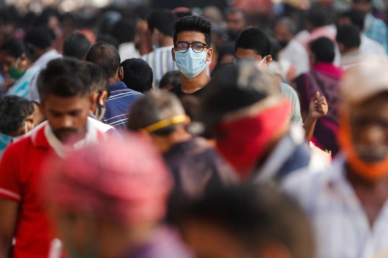 A man wearing a protective mask is seen among people at a crowded market amidst the spread of the coronavirus disease (COVID-19) in Mumbai, India, October 29, 2020. REUTERS/Francis Mascarenhas